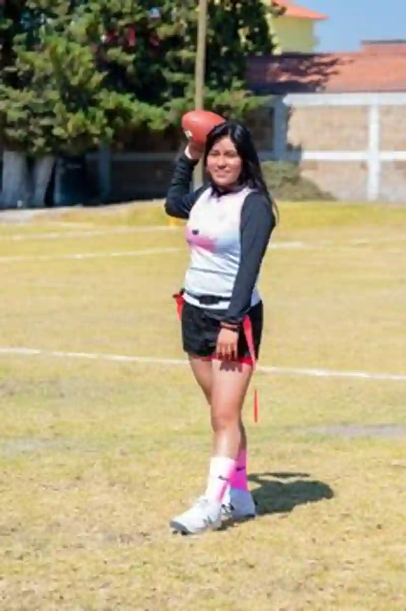 Atlet muda perempuan memegang bola di lapangan yang cerah, mewakili olahraga remaja di Toluca de Lerdo, Meksiko.