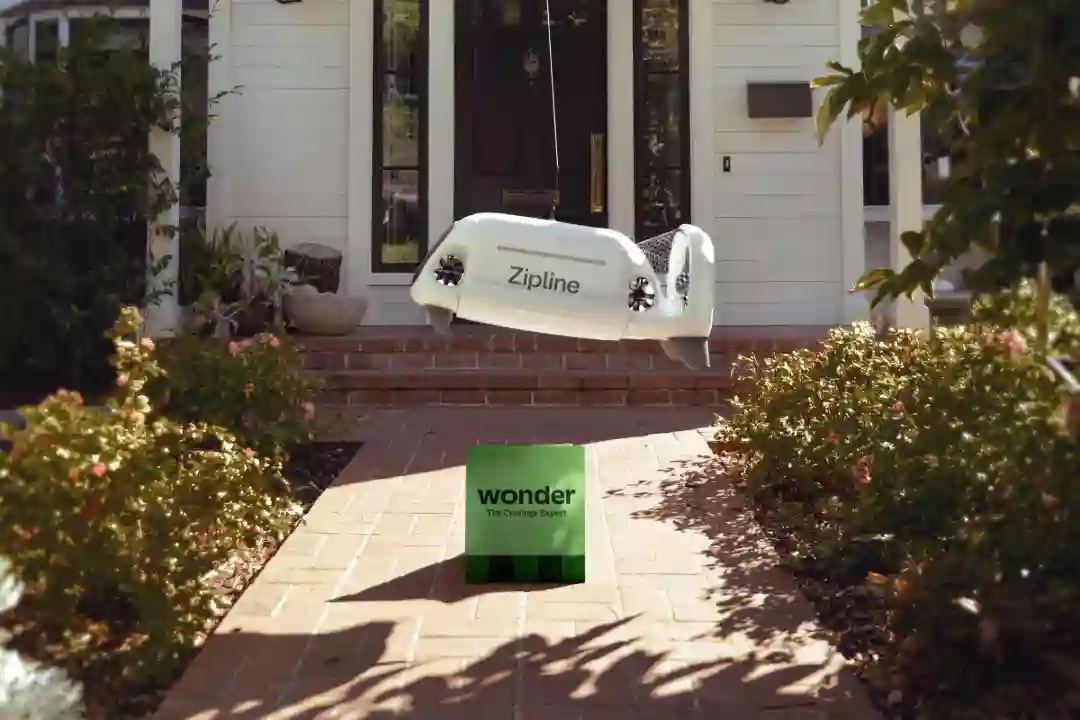 A Zipline drone hovering above a residential area, lowering a package containing a takeaway meal.