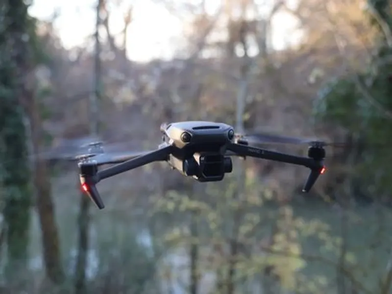 Drone DJI Mavic 3 terbang di atas area hutan yang indah.