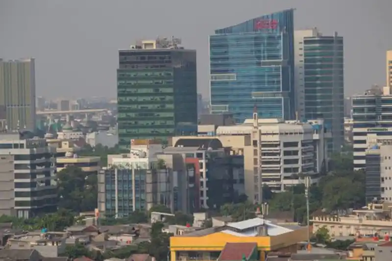Pemandangan udara cakrawala kota Jakarta yang memamerkan gedung pencakar langit modern dan kehidupan kota yang ramai.